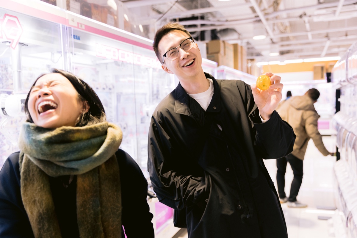 Couple laughing at a gashapon machine in Shinjuku